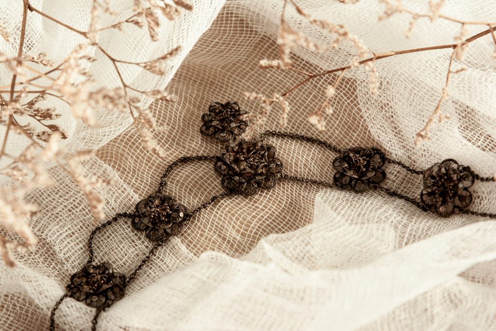 Delicate floral embellishment with dark beaded lace design on soft white mesh fabric — showcasing elegant contrast and texture in hand embroidery.